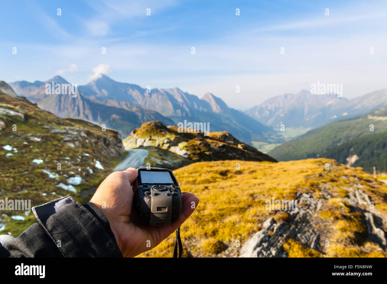 GPS navigator and hand on Alps mountain background Stock Photo