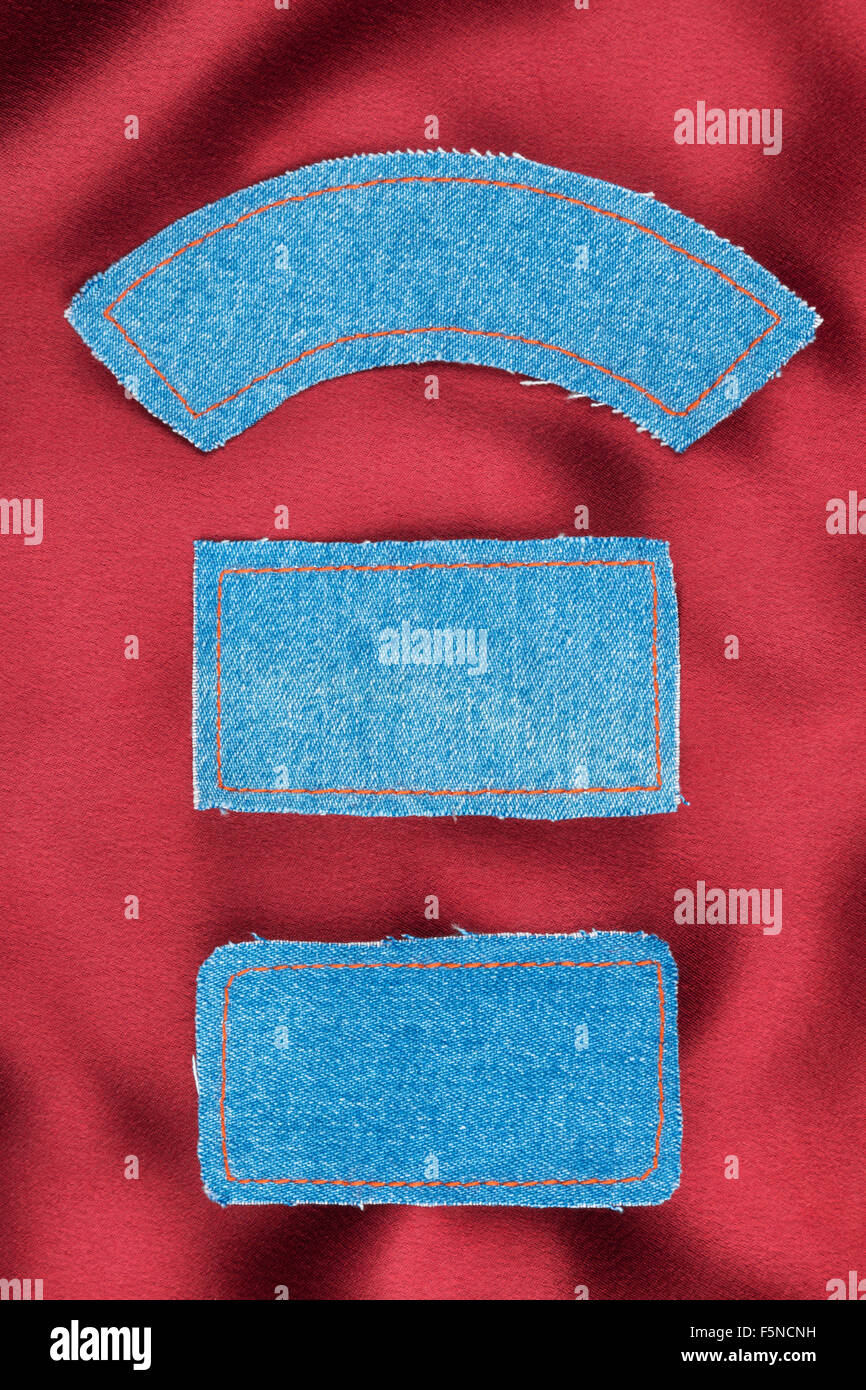 Labels made of jeans lying on the red silk, as background Stock Photo