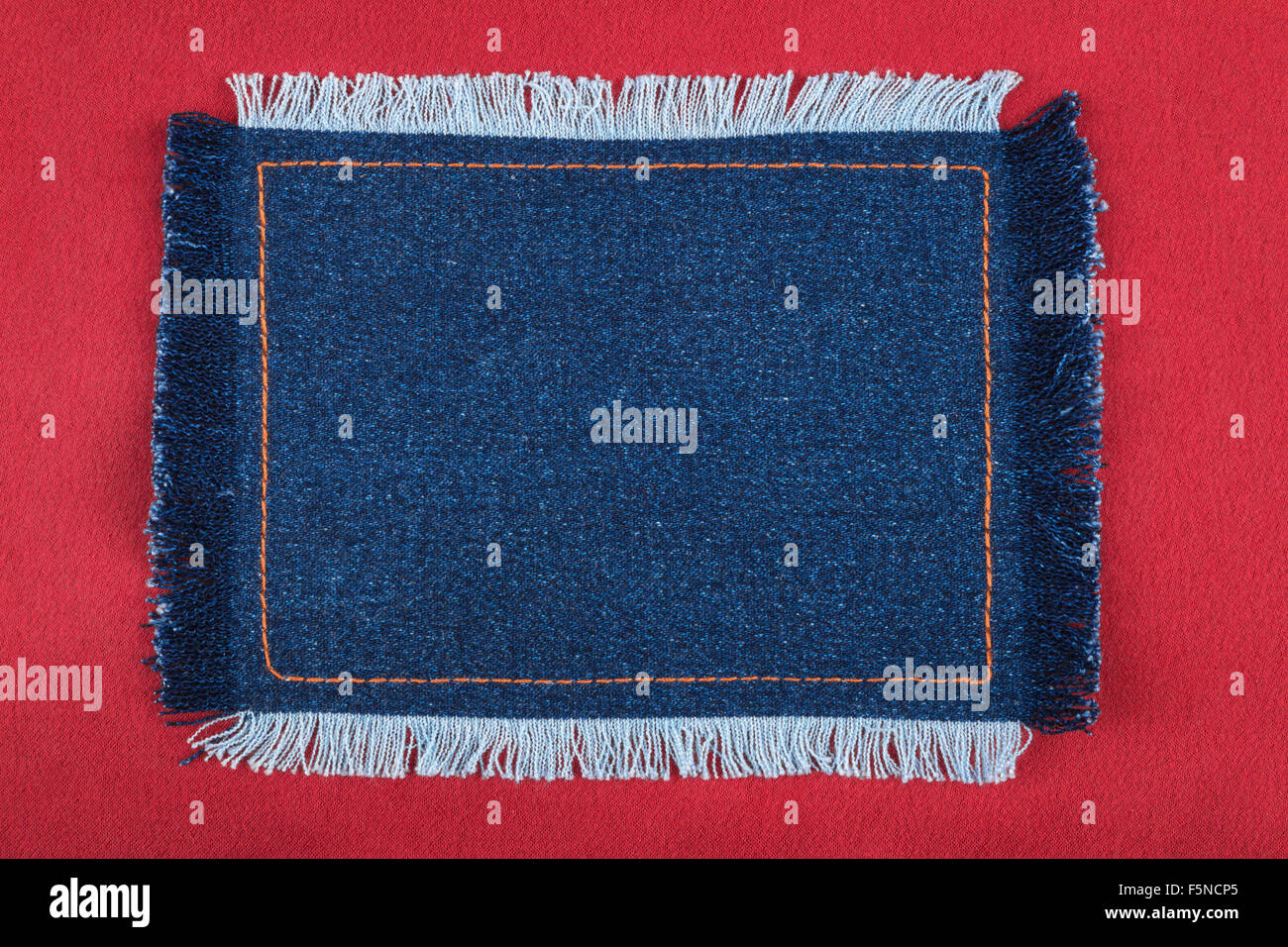 Frame made of denim fabric with yellow stitching on red silk, with space for your text Stock Photo