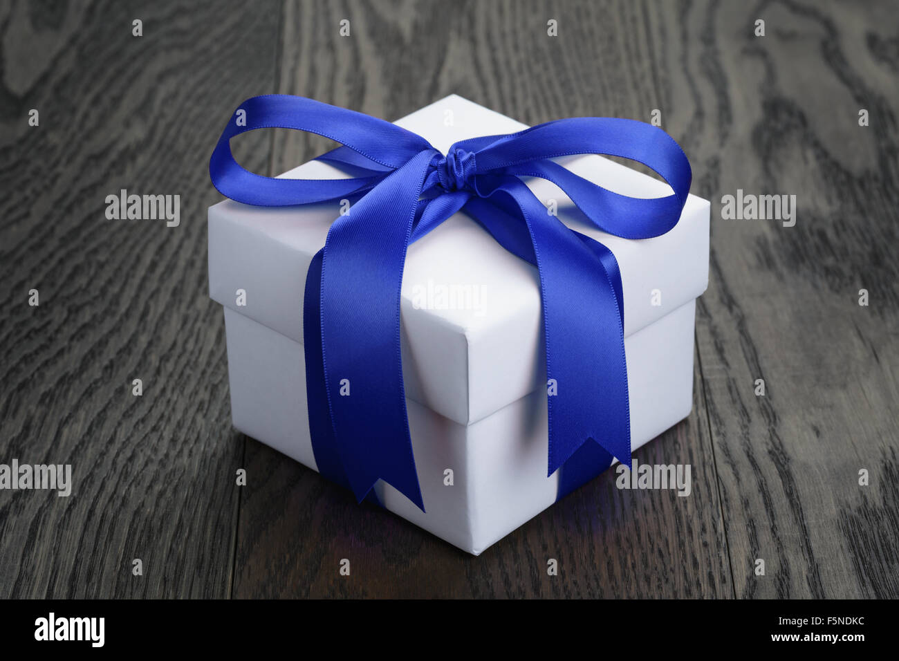gift box with blue bow on rustic table Stock Photo