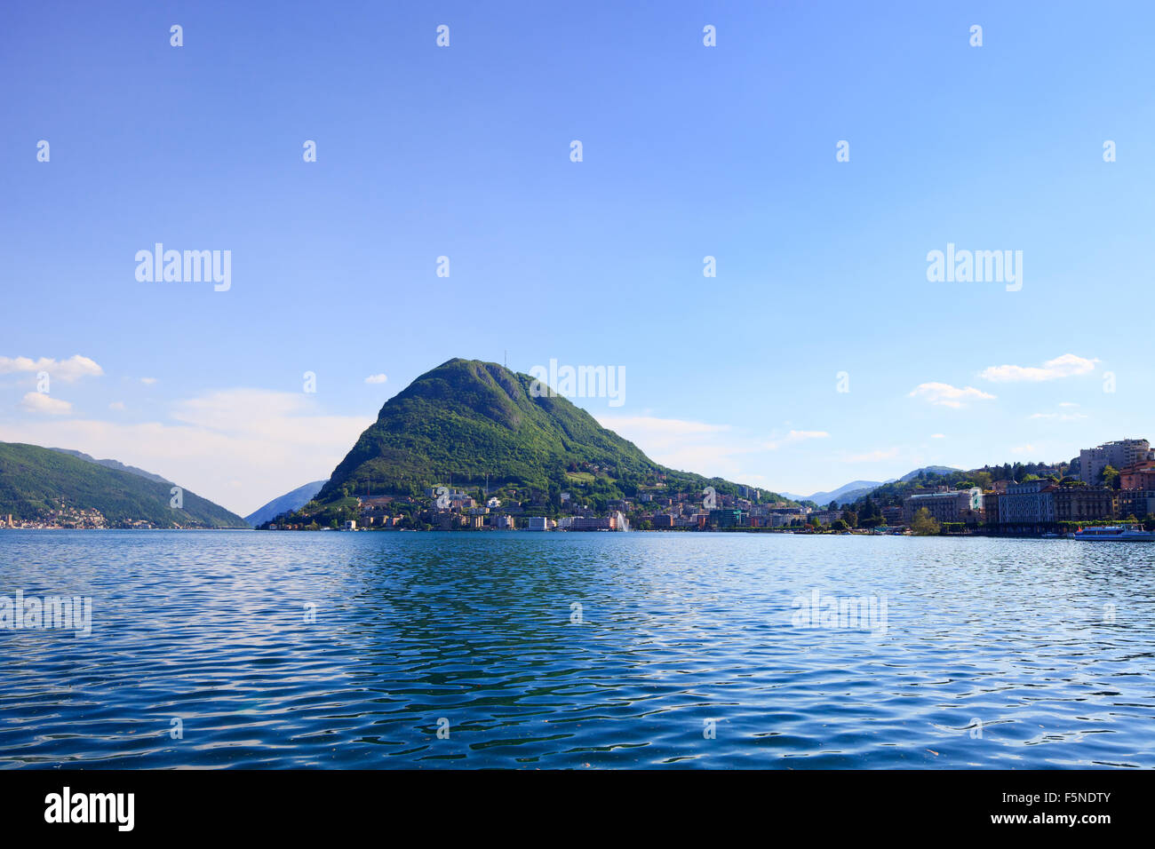 Lugano lake and mountains landscape. City, water, blue sky and mountains. Ticino, Swiss or Switzerland, Europe. Stock Photo