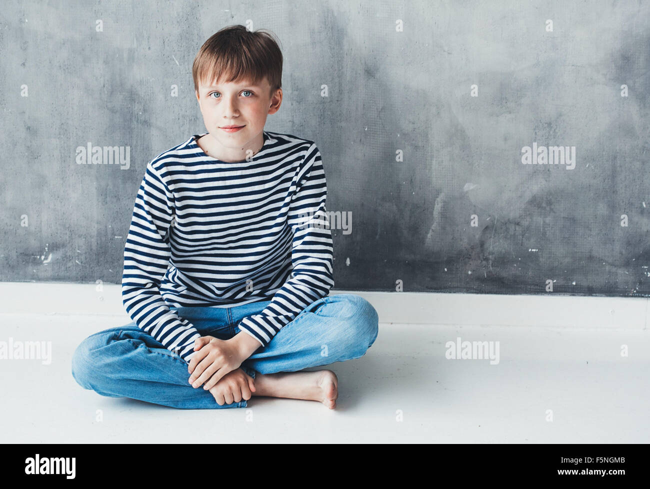 Cute boy happy beautiful child studio closeup portrait stripes sitting near gray background wall Stock Photo