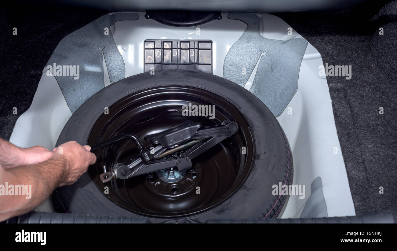Removing spare tire and jack from trunk Stock Photo Alamy