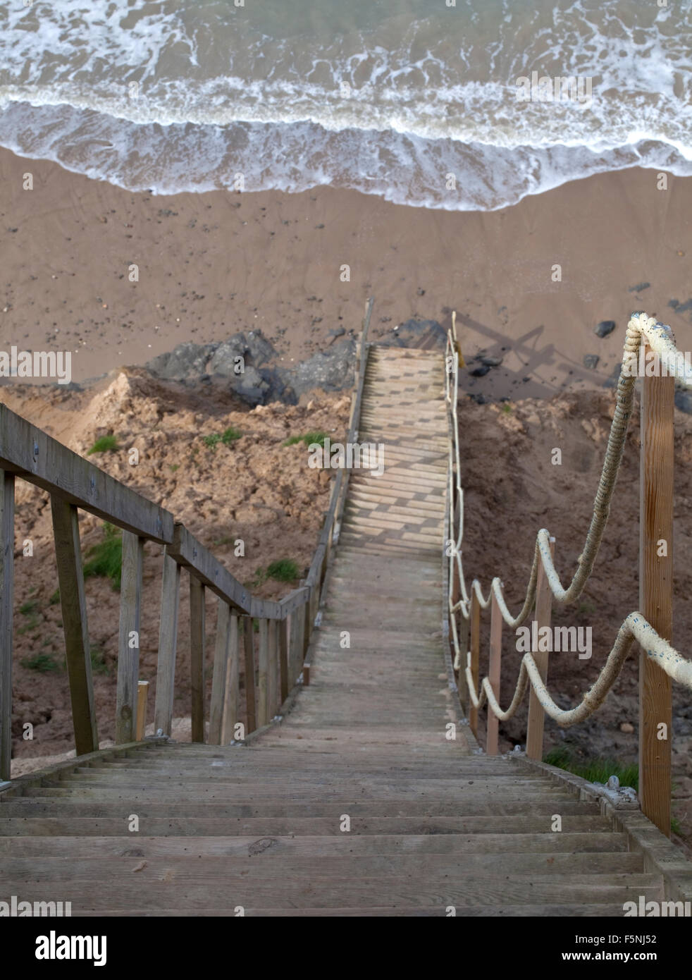 A steep staircase traverses an unstable cliff side to get people down to the sea shore. It is a long way down. Stock Photo