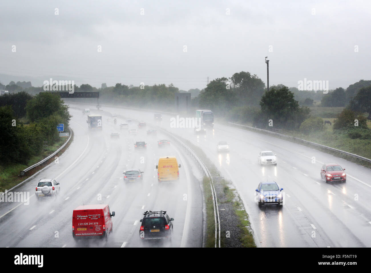 Vehicles using a busy M5 motorway in Somerset during a rain storm with lots of spray  making visibility poor and very difficult driving conditions Stock Photo