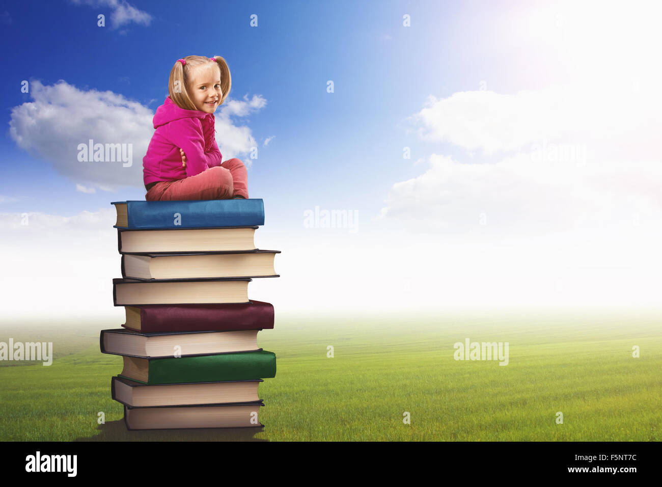 Small girl sits on the pile of books on nature background Stock Photo ...