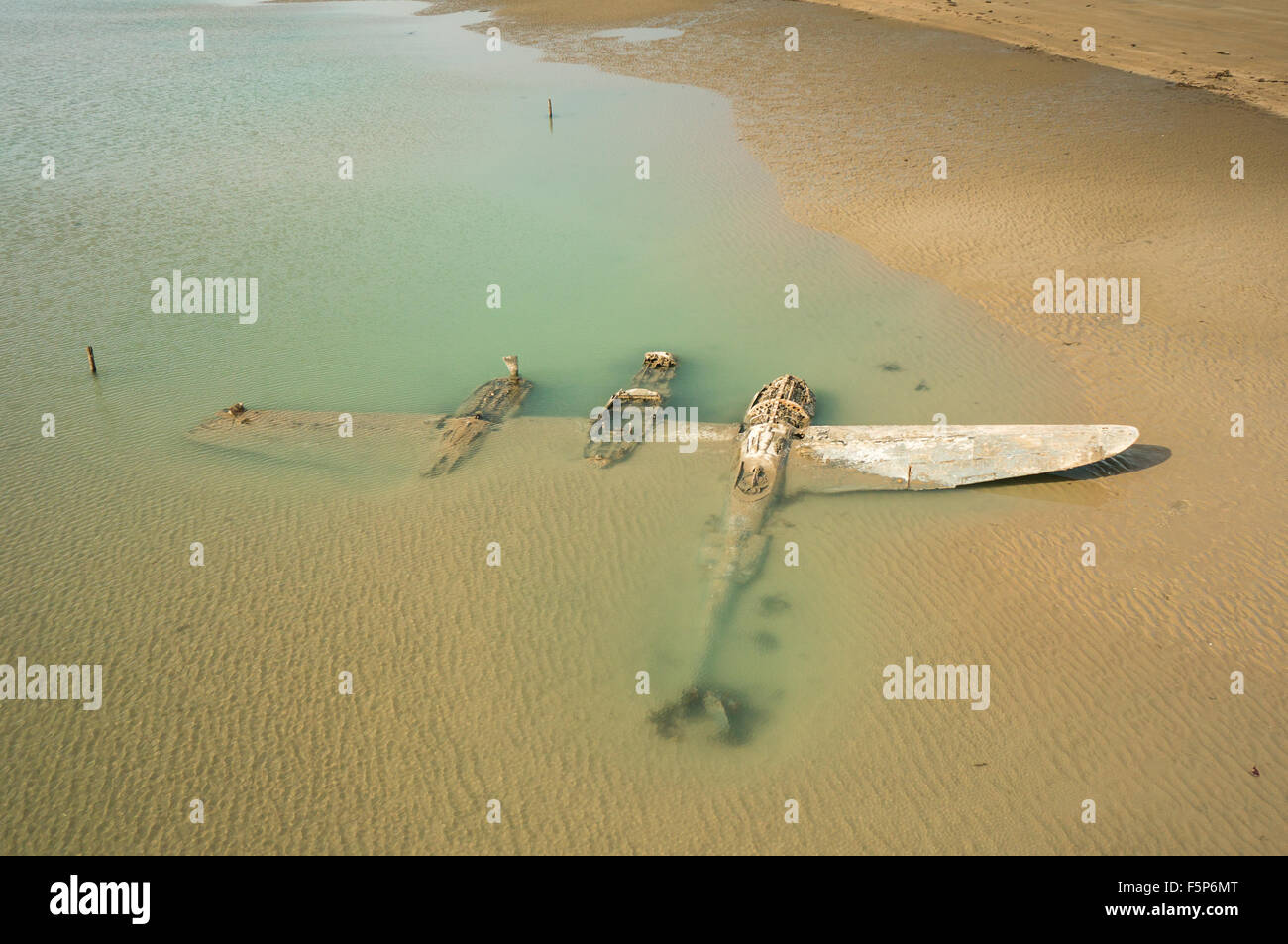 The wrech of a crashed WW2 P38 Lightning Aircraft laying on a beach in Wales, UK Stock Photo