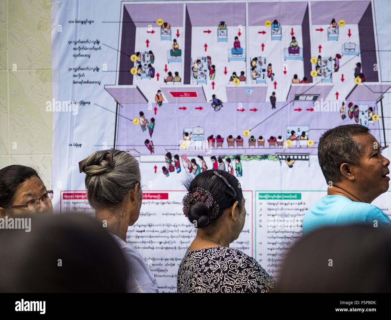 Yangon, Yangon Division, Myanmar. 8th Nov, 2015. People stand in line to get into their polling place in North Okkalapa, a township outside of central Yangon. A schematic drawing of the voting process is on the wall behind them. The citizens of Myanmar went to the polls Sunday to vote in the most democratic elections since 1990. The National League for Democracy, (NLD) the party of Aung San Suu Kyi is widely expected to get the most votes in the election, but it is not certain if they will get enough votes to secure an outright victory. The polls opened at 6AM. © ZUMA Press, Inc./Alamy Stock Photo