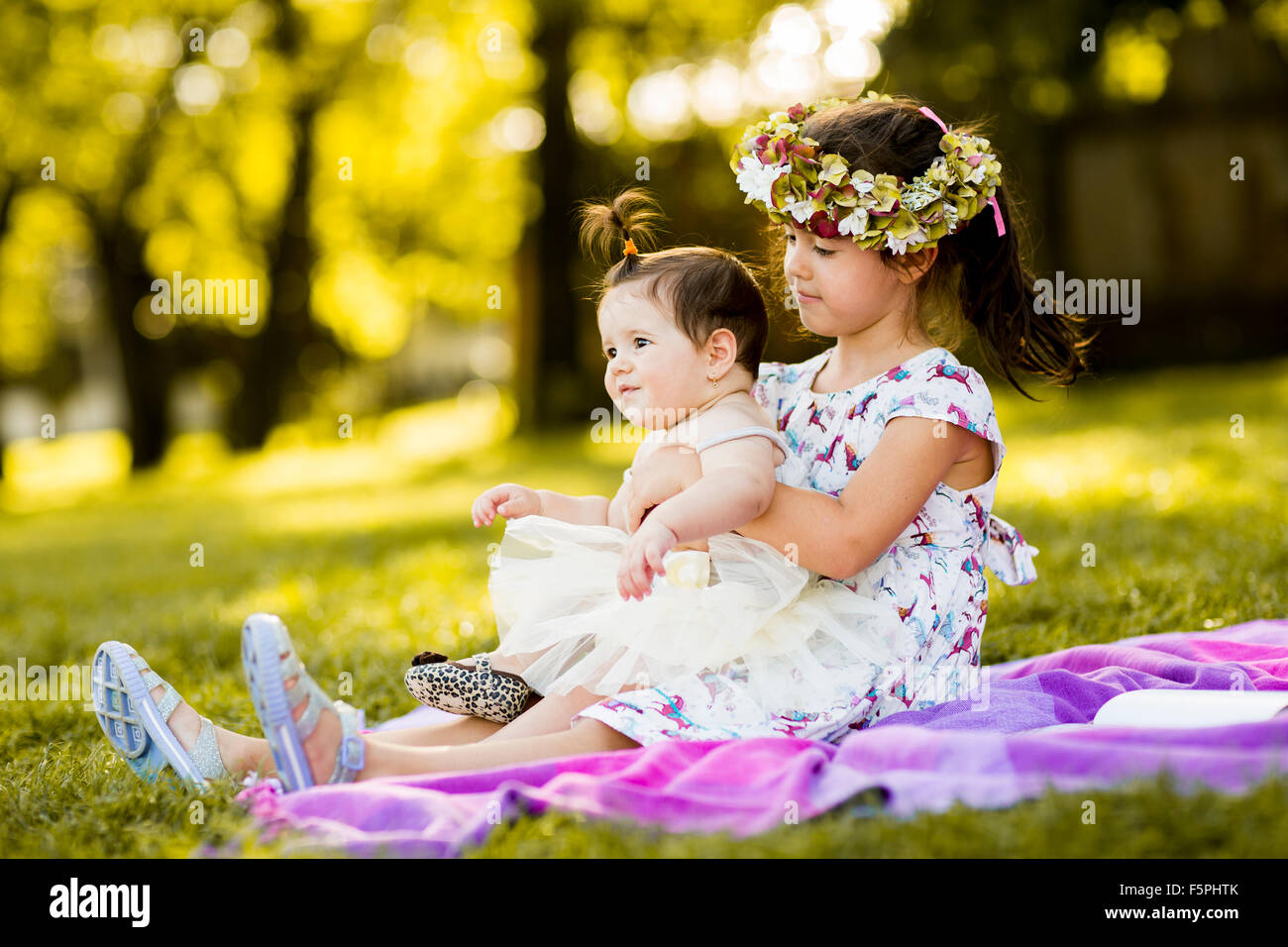 Little girl and baby sitting in the grass Stock Photo
