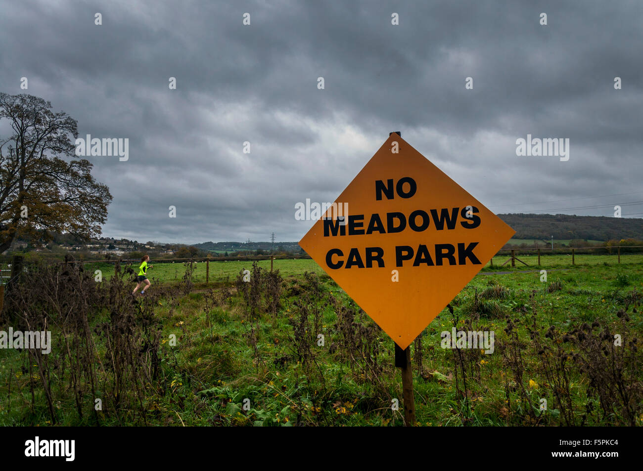 Bathampton, Bath, Somerset, UK. 8th November 2015. A morning jogger passes campaign sign to stop the potential building of a park and ride carpark on ancient water meadows (in background) in Bathampton near Bath.  Photo by:Richard Wayman/Alamy Live News Stock Photo
