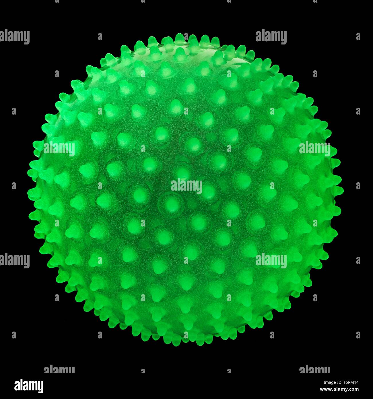 Green fluorescent spiky ball against a black background. Stock Photo