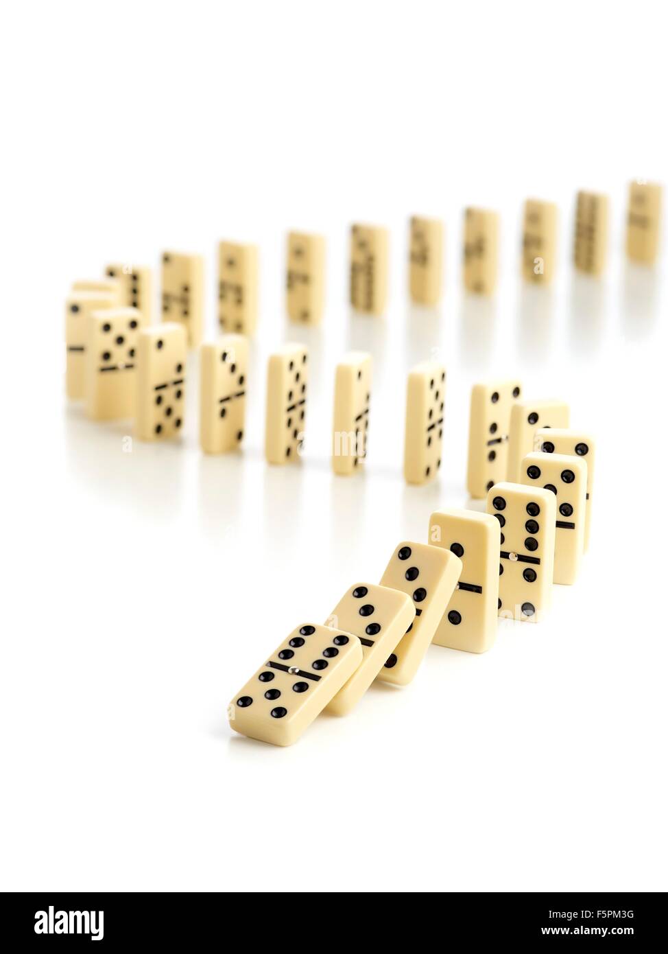 Dominoes falling down against a white background. Stock Photo