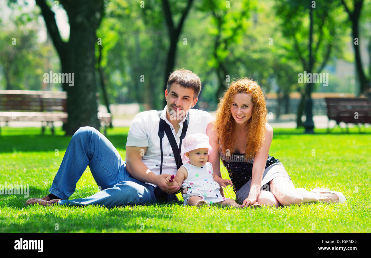Happy family on a grass in park Stock Photo - Alamy