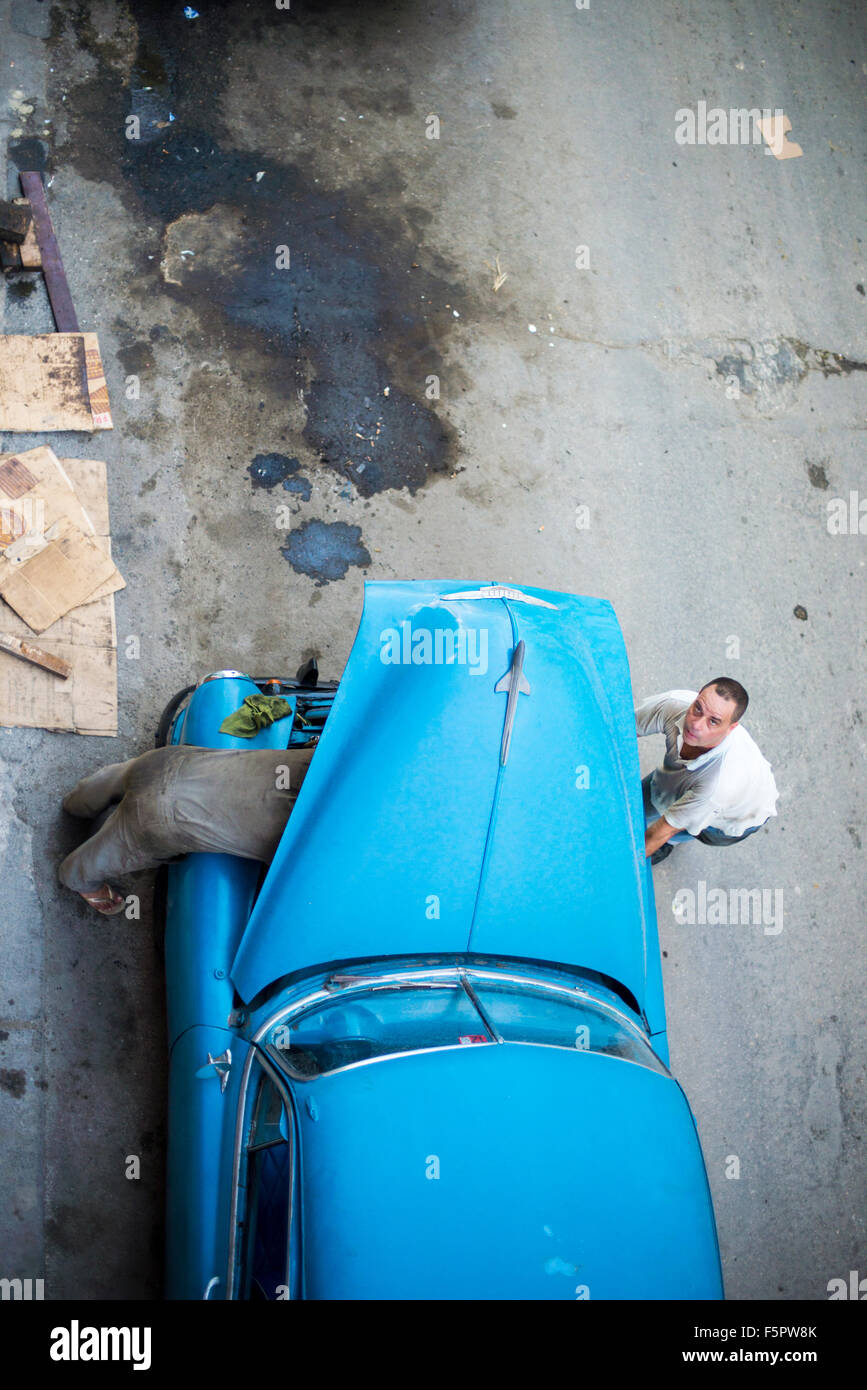 Two men working on the engine of their classic American car, Havana, Cuba Stock Photo