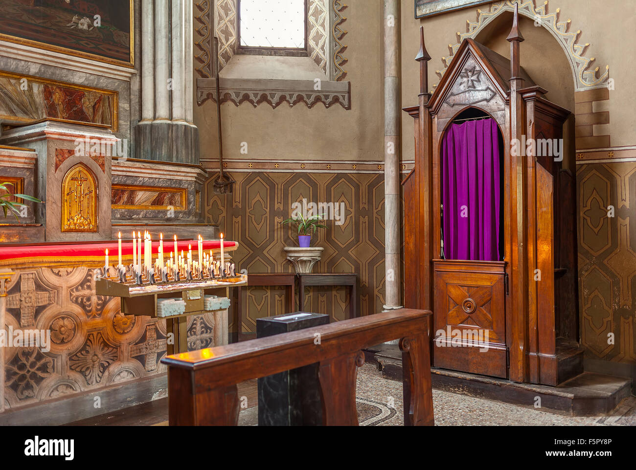 Wooden confessional and altar with candles in San Lorenzo Cathedral in Alba, Italy. Stock Photo