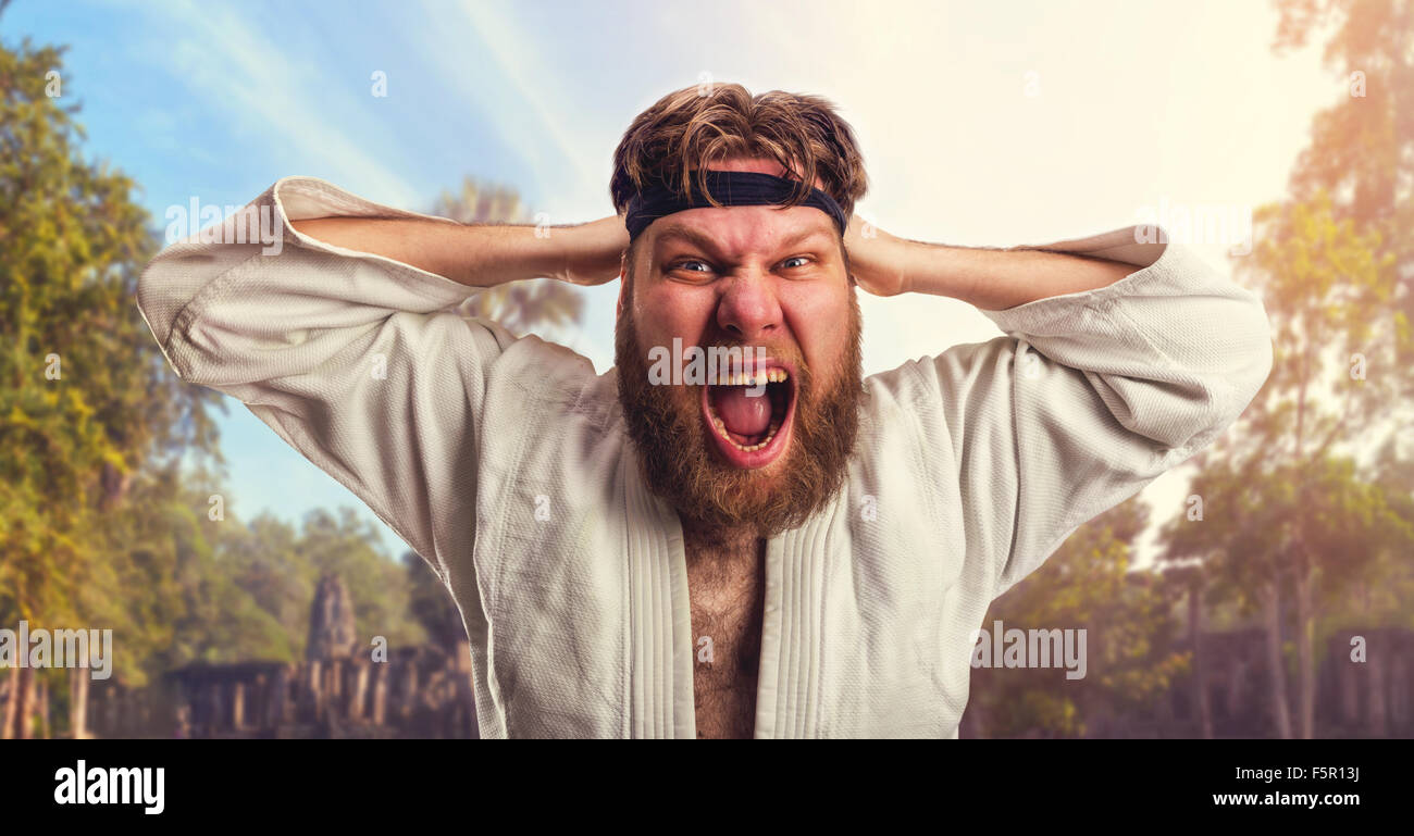 Aggressive karateka is tightening the black belt on his head Stock Photo