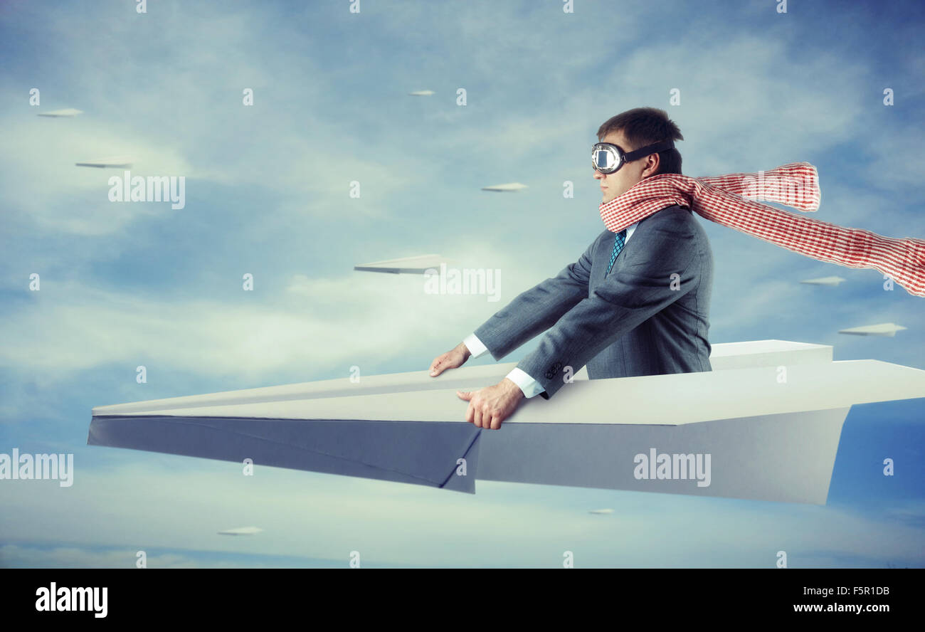 Businessman flying on big paper plane and wearing goggles and scarf