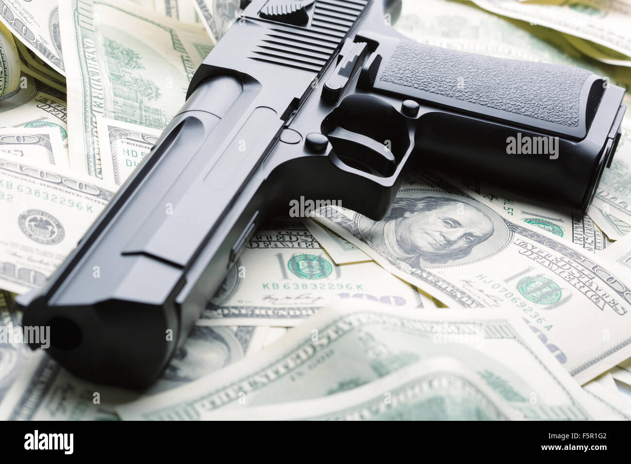 Heap of $100 dollar bills and handgun Stock Photo