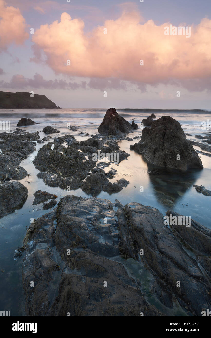 Sunrise over Hope Cove, Devon as the incoming tide covers the rocks on the beach. Stock Photo