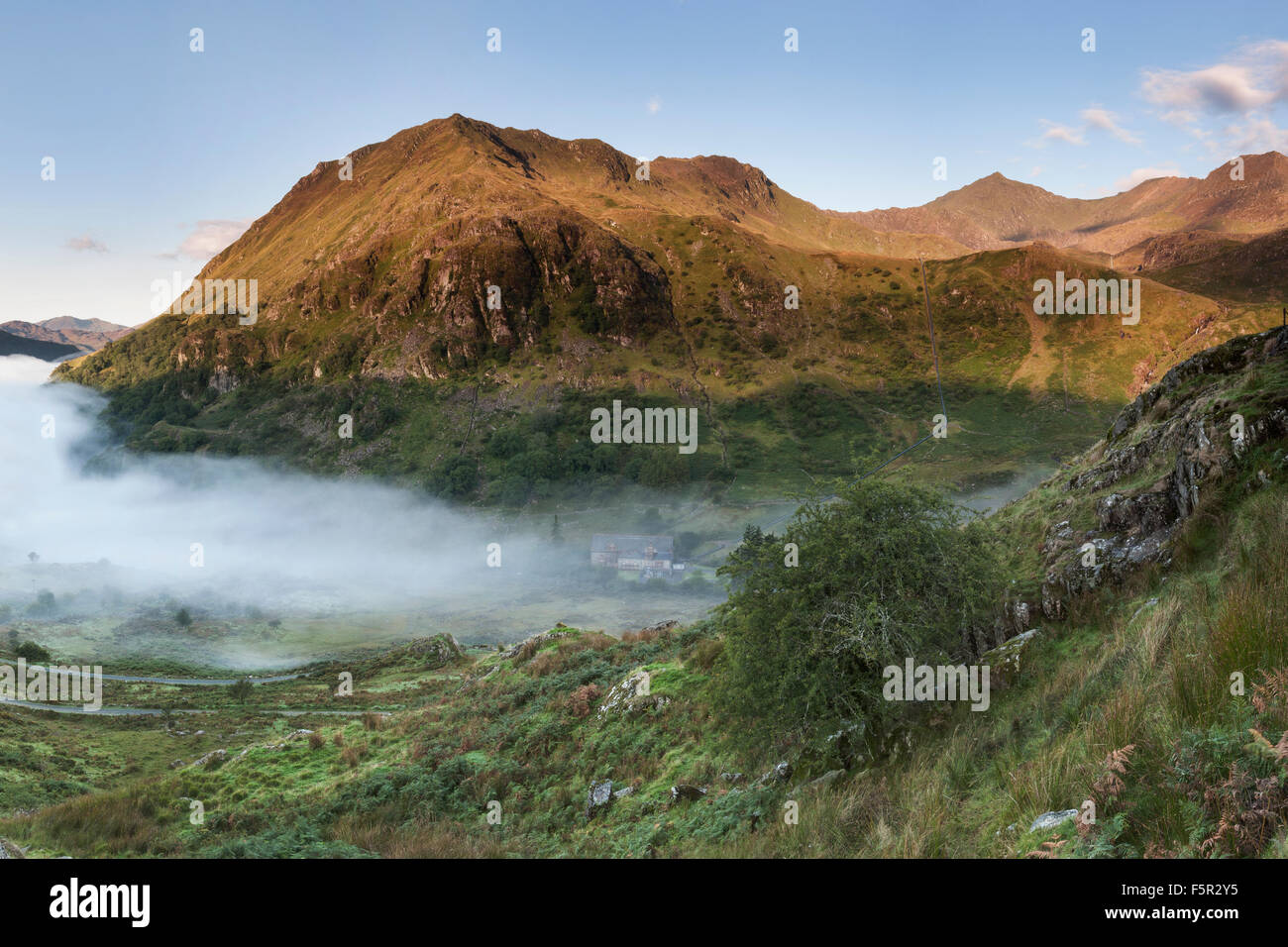A clear sky has allowed the sunrise to light up Gallt Y Wenallt, Snowdon and Crib Goch. Mist fills the Gwynant valley Stock Photo