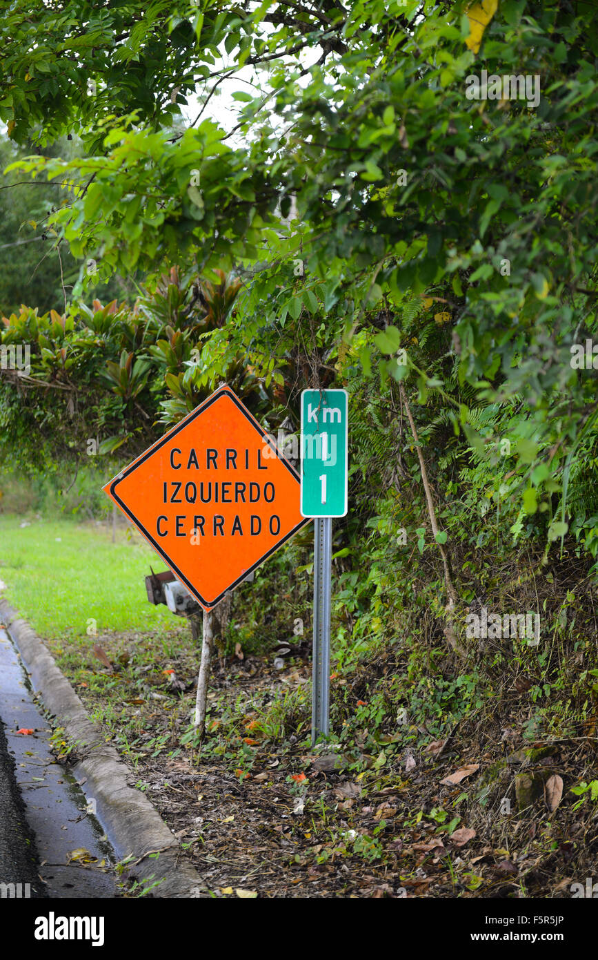 Traffic sign: left lane closed. Distance is measured in kilometers. Cayey, Puerto Rico. USA territory. Caribbean Island. Stock Photo