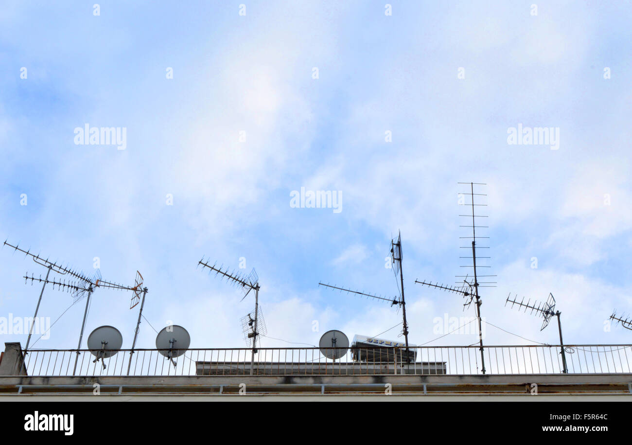 Antennas and TV satellite dish on roof against blue sky. Stock Photo