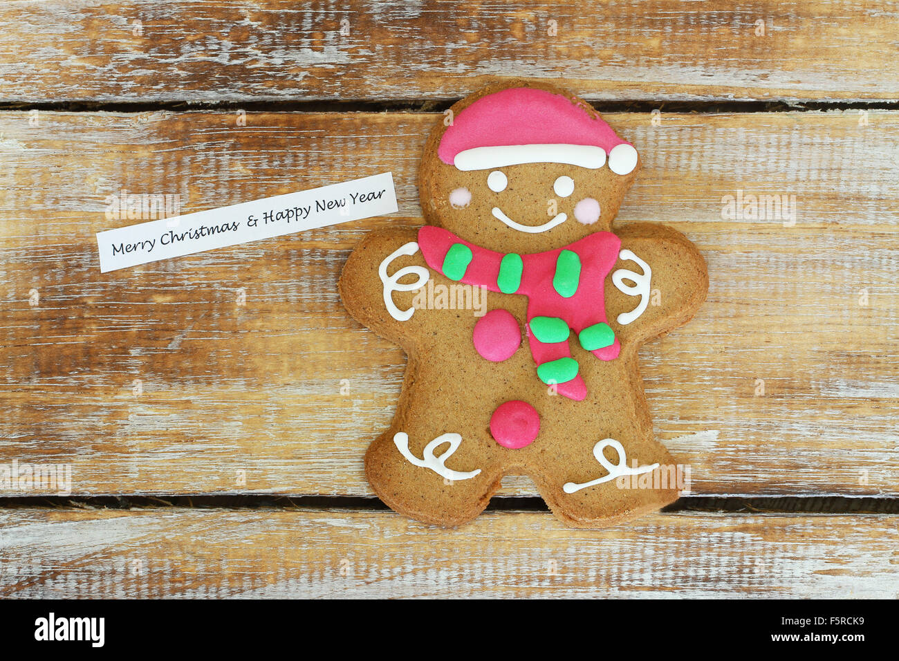 Merry Christmas & Happy New Year card with gingerbread man on wooden surface Stock Photo