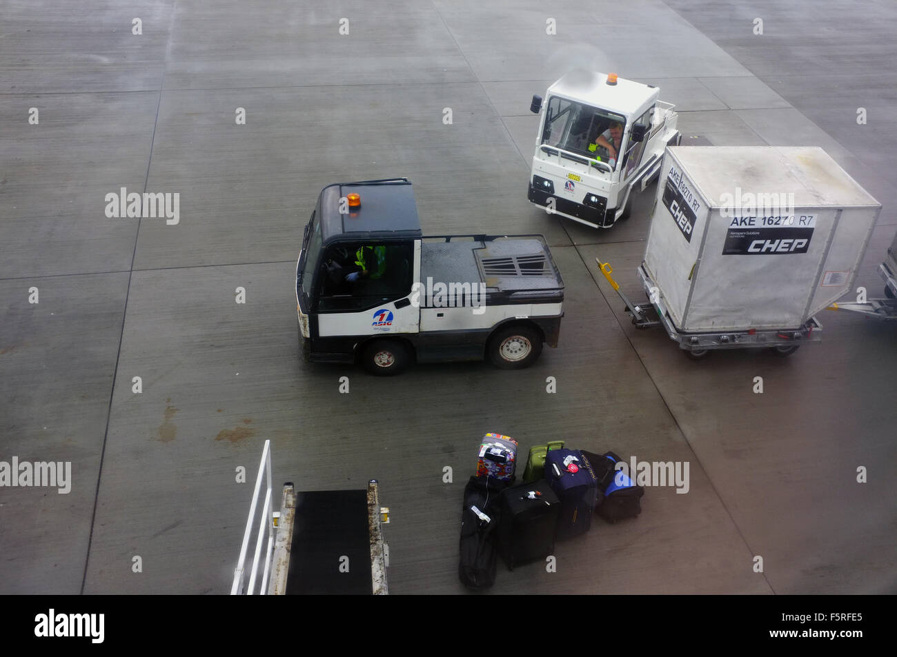 Airport baggage handling vehicles on the ground at Heathrow Airport in
