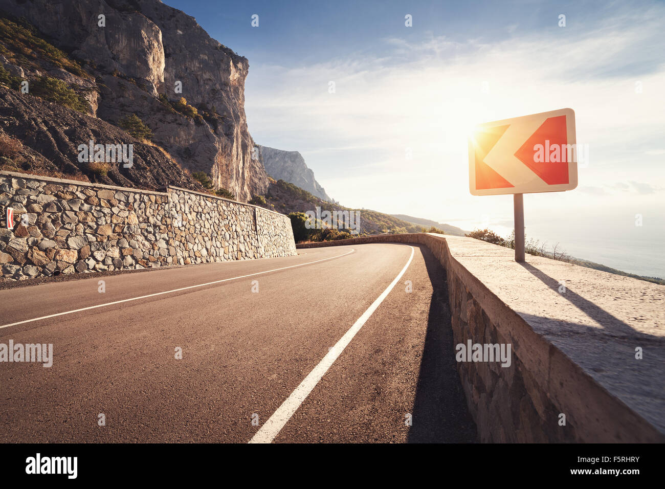 Asphalt road in autumn forest at sunrise. Crimean mountains. Stock Photo