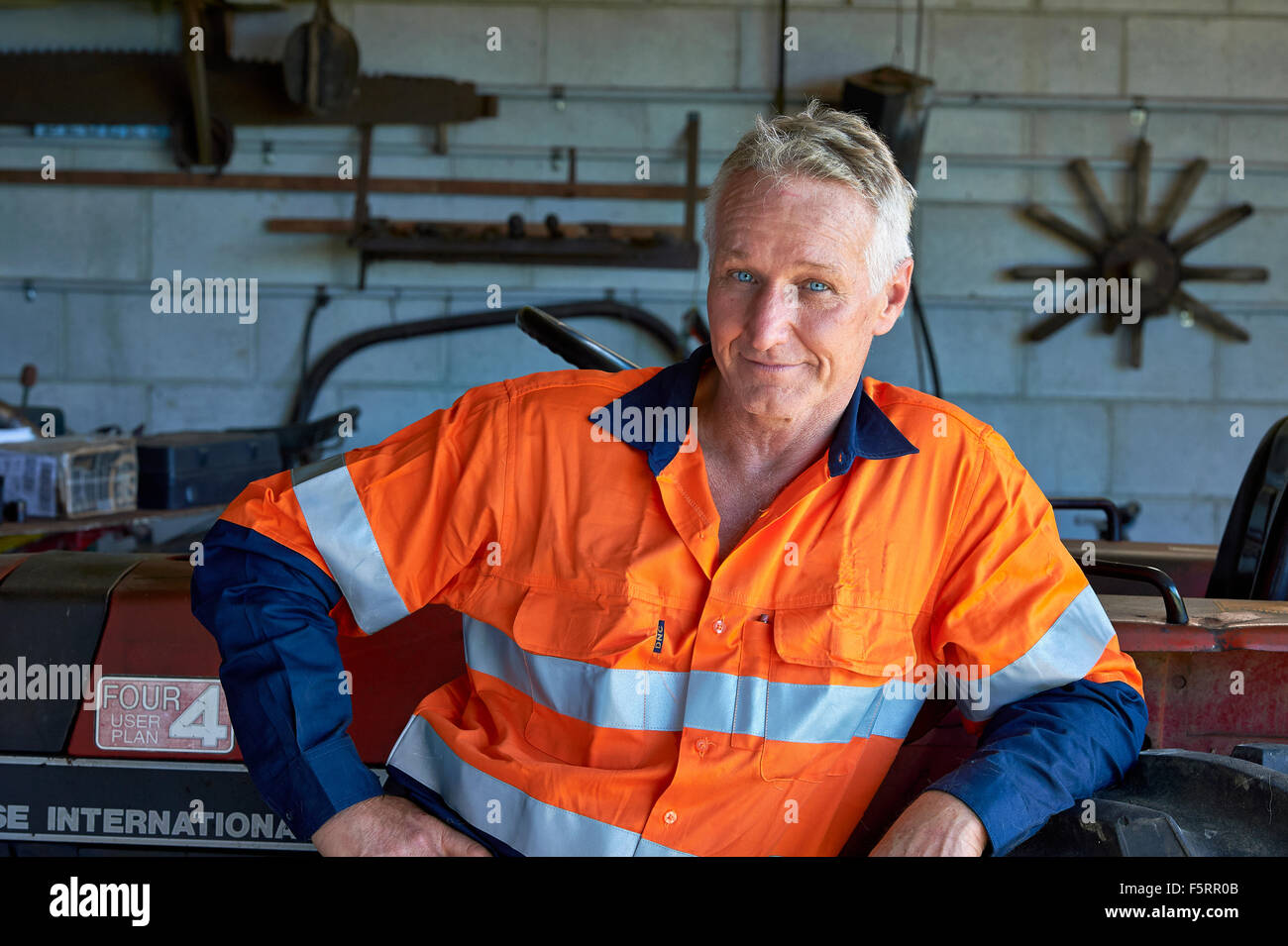 Portrait of a farmer in safety cloths next to his tractor Stock Photo