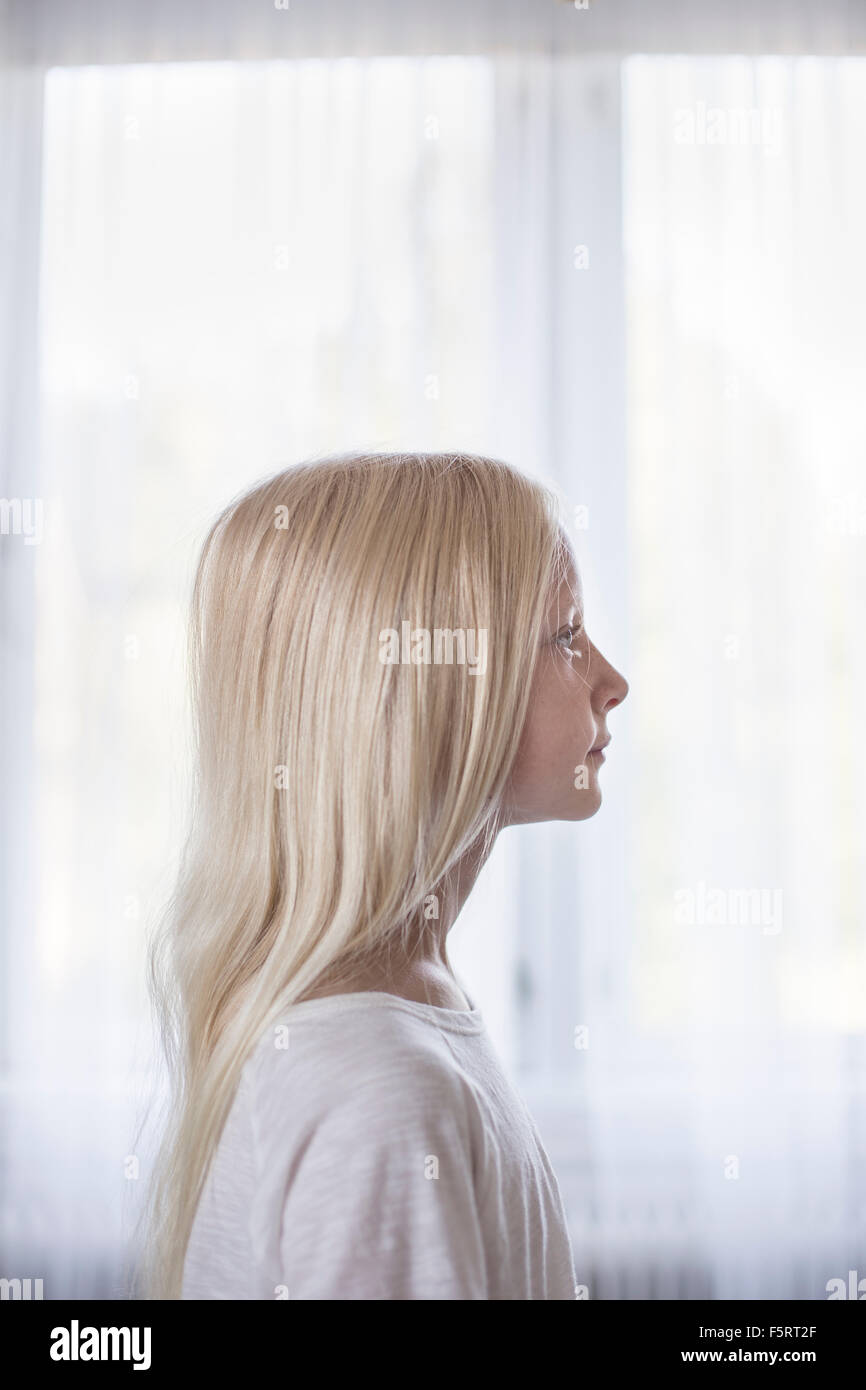 Sweden, Side view of blonde girl (10-11) in front of white curtains Stock Photo