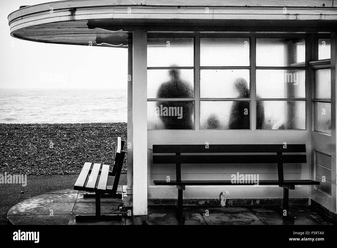 A family shelter from the rain in a seafront shelter, photographed