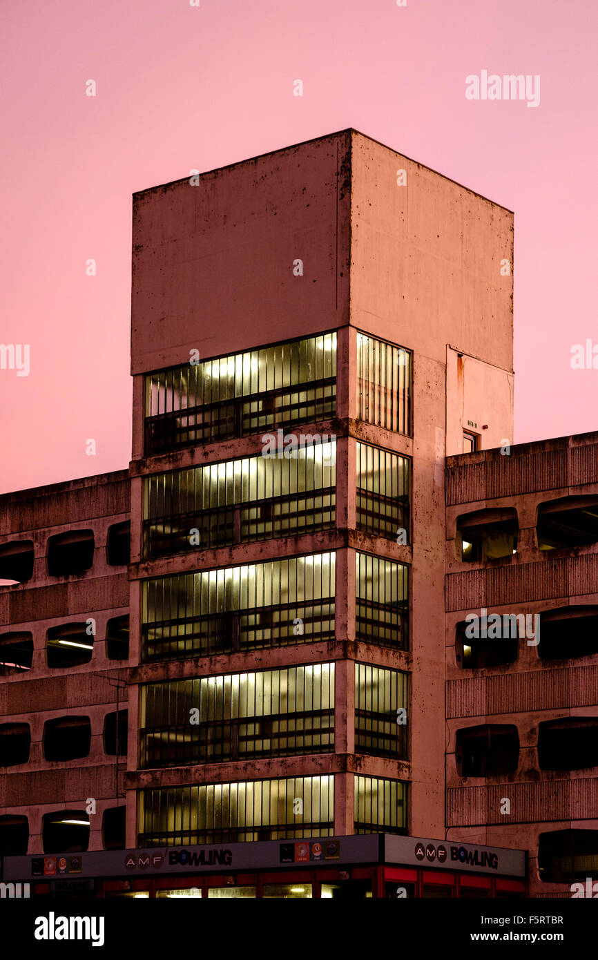 The staircase tower and lights of a concrete multi story car park in the orange morning sunrise light Stock Photo