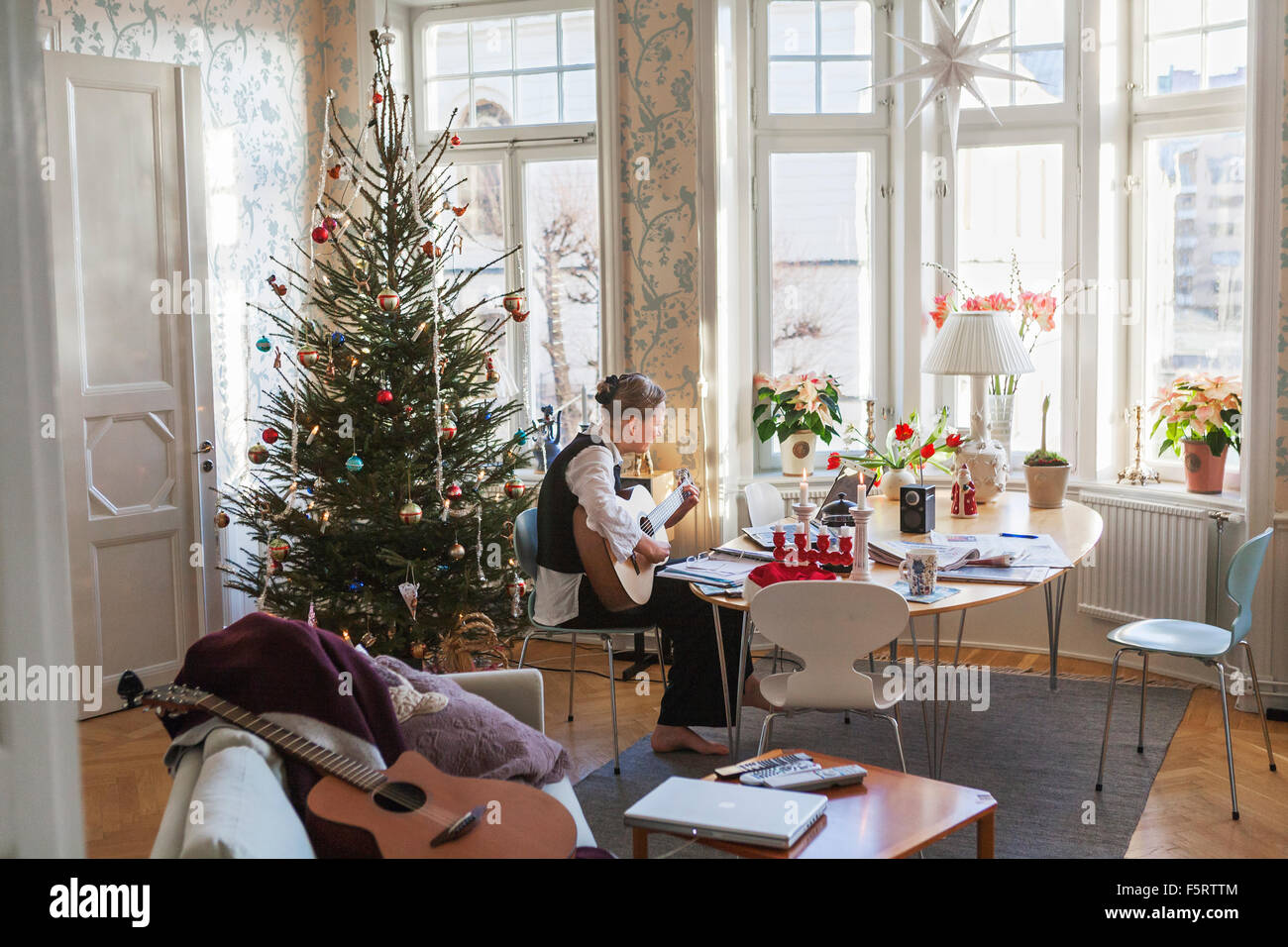 Sweden, Senior woman playing guitar in living room Stock Photo