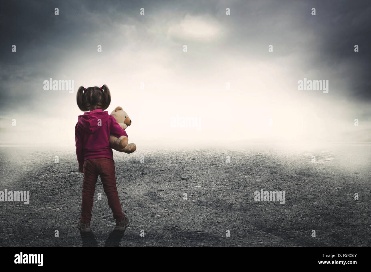 Little girl standing back with toy bear in the darkness Stock Photo - Alamy