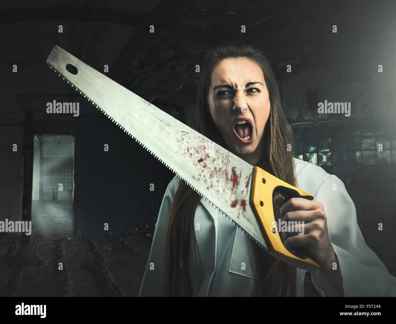 Scary portrait of an angry crazy woman with a bloody saw in her hand Stock Photo