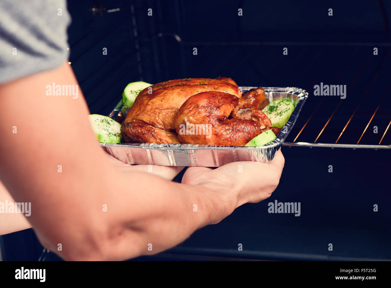 closeup of a young caucasian man preparing an appetizing roast turkey in the oven Stock Photo
