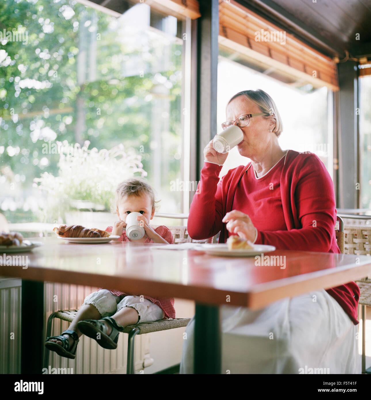 Finland, Helsinki, Uusimaa, Grandmother and granddaughter (2-3) relaxing in cafe Stock Photo