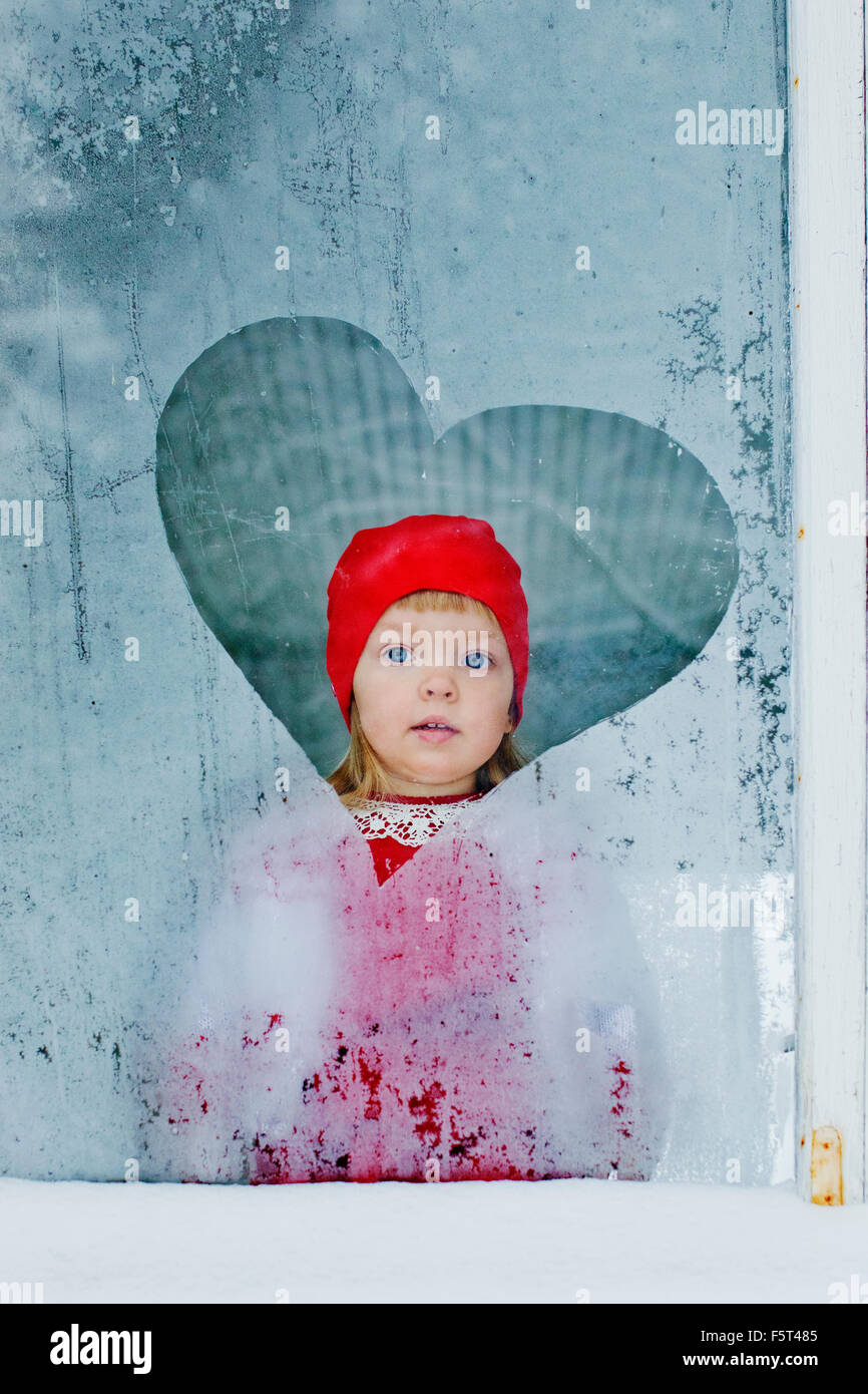 Portrait of girl (4-5) looking through frozen window Stock Photo