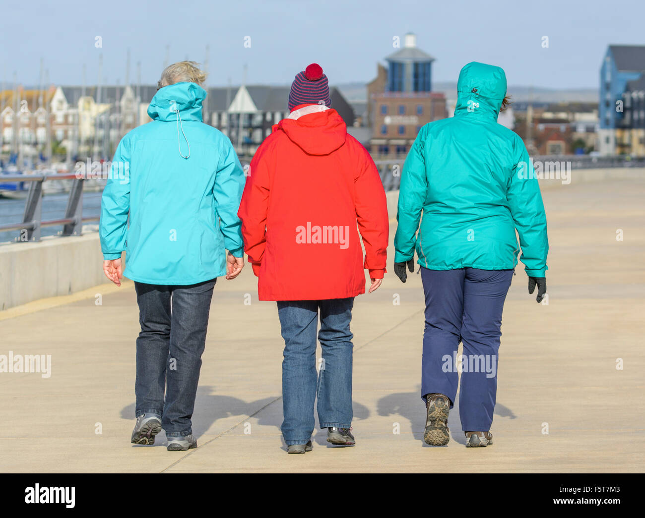 3 women wearing coats, walking away on a cold damp day in Winter in West Sussex, England, UK. Stock Photo