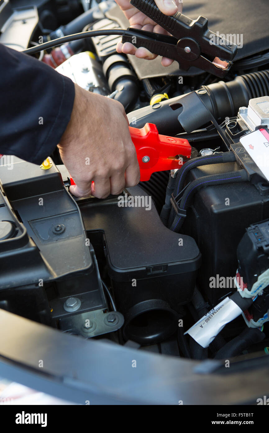 Close-Up Of Mechanic Attaching Jumper Cables To Car Battery Stock Photo