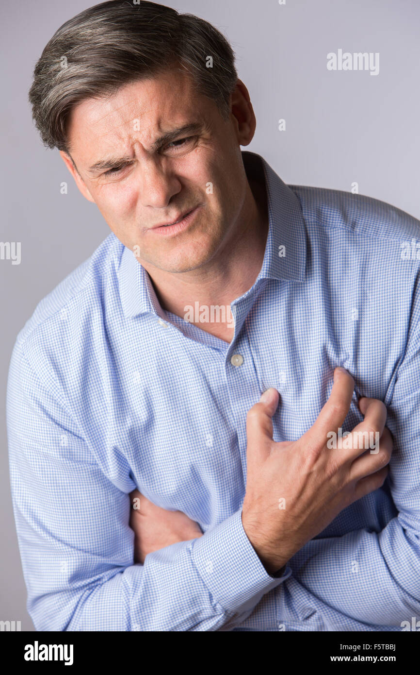 Studio Shot Of Mature Man Suffering Heart Attack Stock Photo