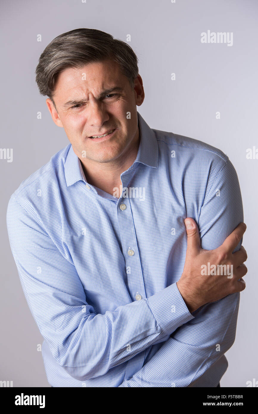 Studio Of Mature Man Clutching Arm As Warning Of Heart Attack Stock