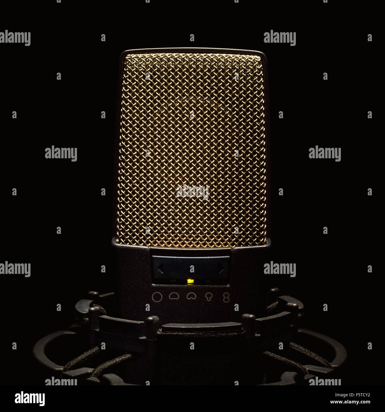 Black modern microphone on stand, black dark background. Accentuated shapes with light. Stock Photo