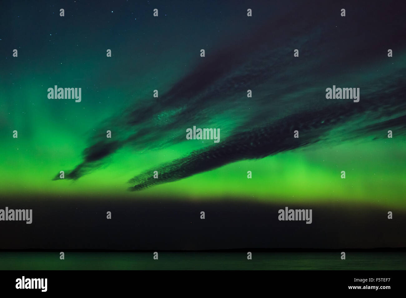 Northern lights and dark clouds over lake in finland Stock Photo - Alamy