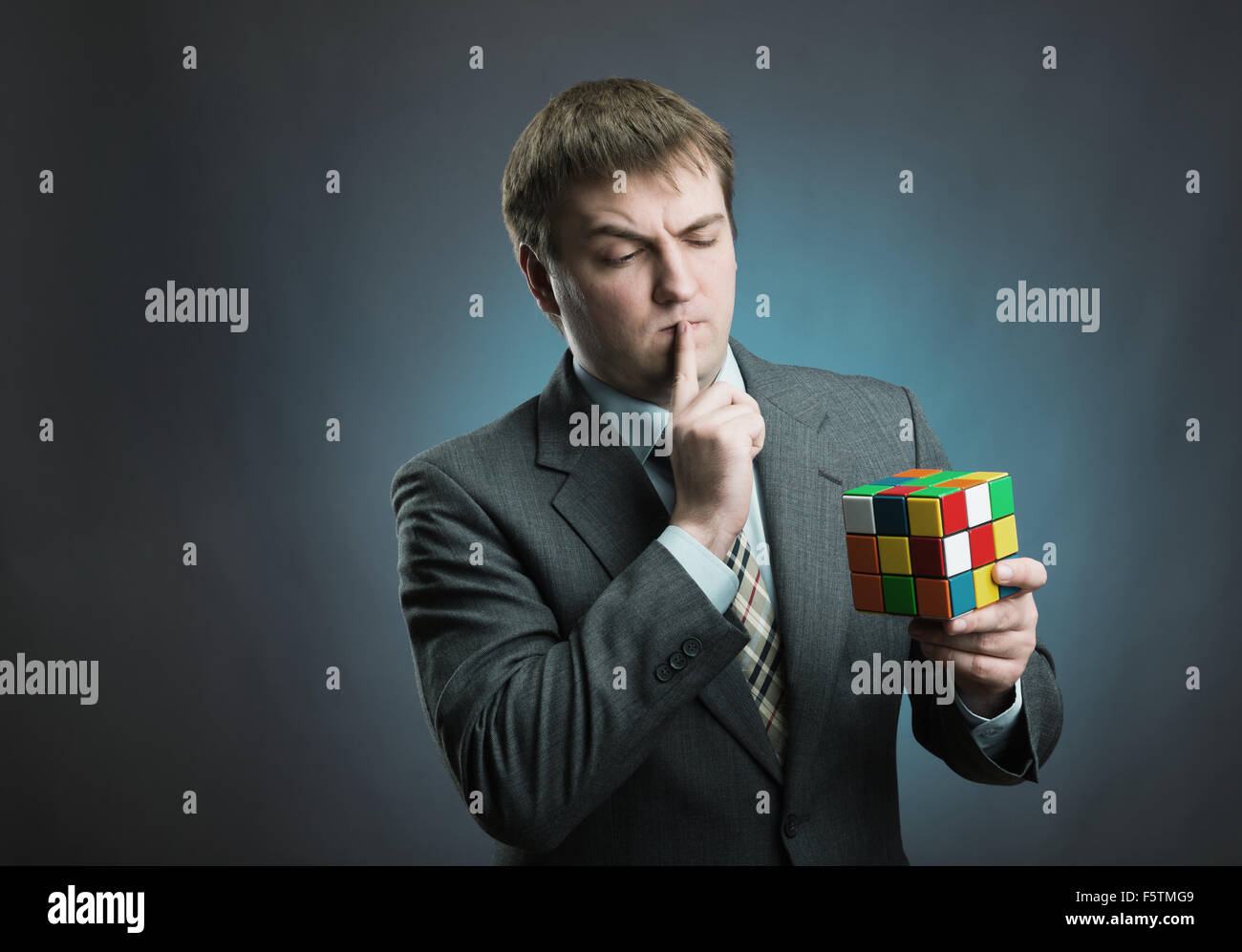 Businessman thinking how to solve rubik cube Stock Photo