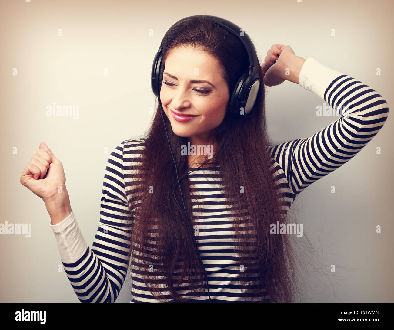 Young beautiful woman listening the music from headphones with dancing. Vintage closeup portrait Stock Photo