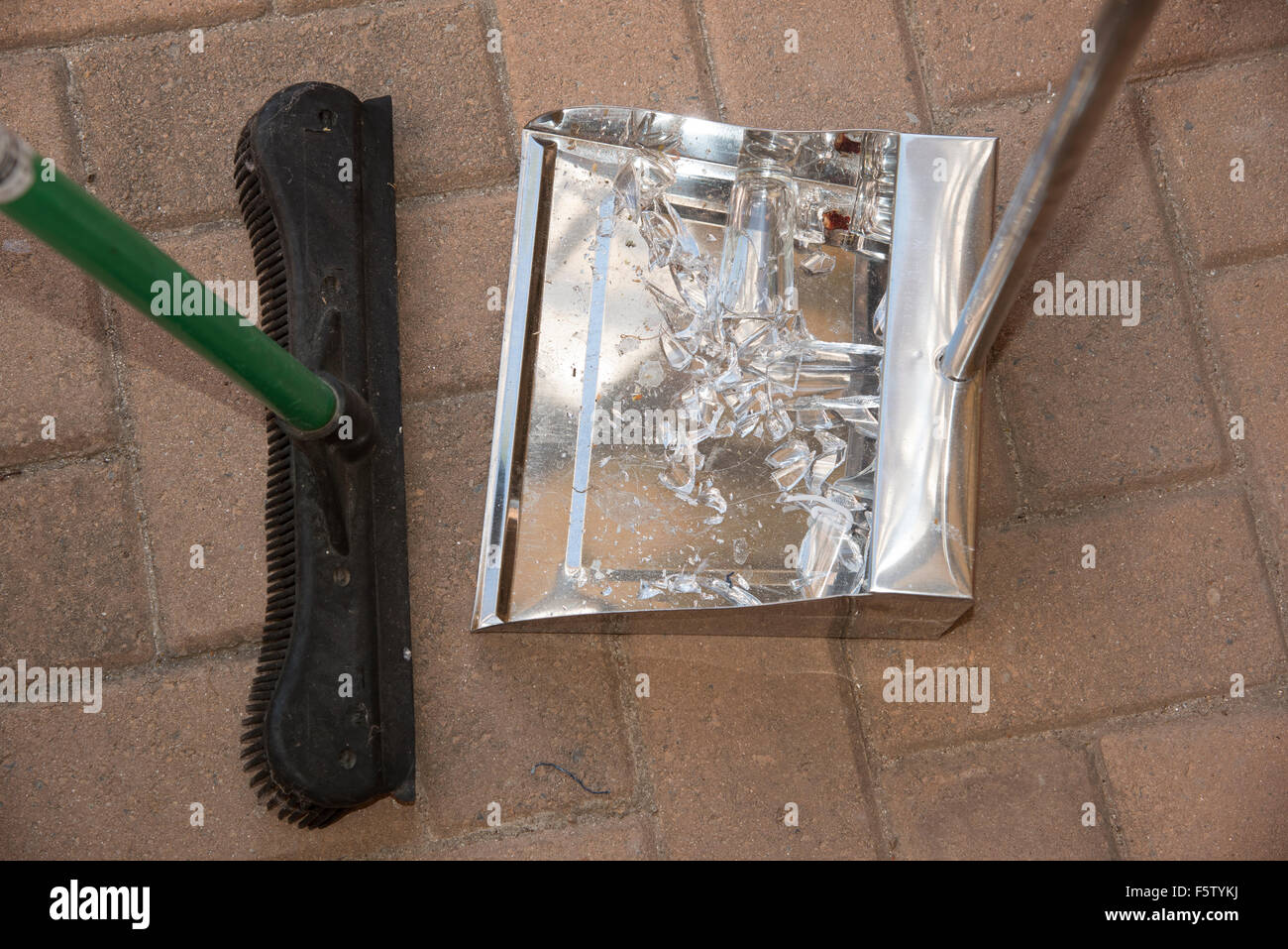 Broken glass having been swept into a dustpan with a broom Stock Photo