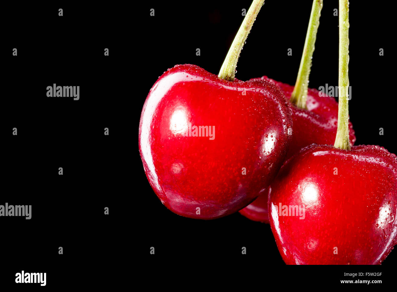 Three berries of cherry isolated on black background Stock Photo