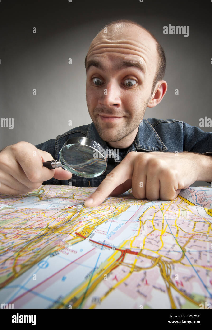 Funny nerd tourist discovering map with magnifier Stock Photo